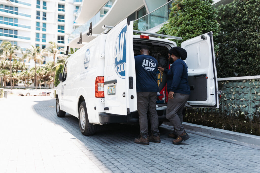 Two A&I plumbing experts removing a water heater from their work van.